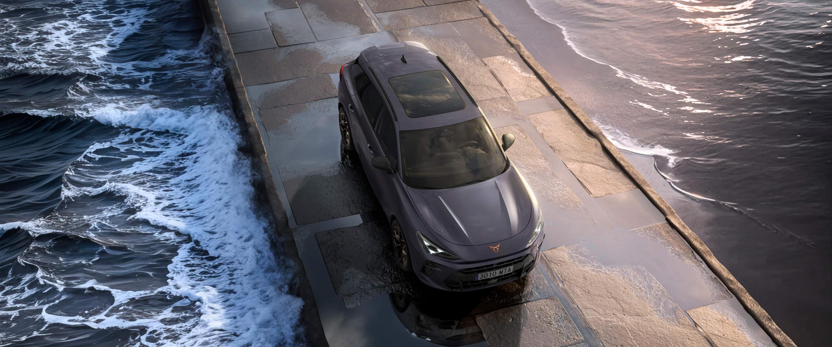 Cupra terramar hibridinis SUV ant šlapio grindinio prie jūros: elegantiški priekiniai žibintai, modernūs lengvojo lydinio ratlankiai ir ryklio galvą primenantis priekis.
